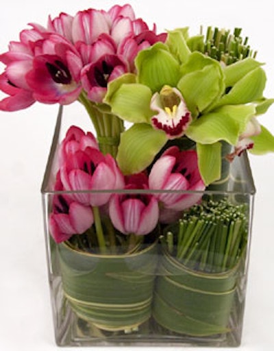 An arrangement of cymbidium orchids and tulips rolled in flax leaves with grass detail.