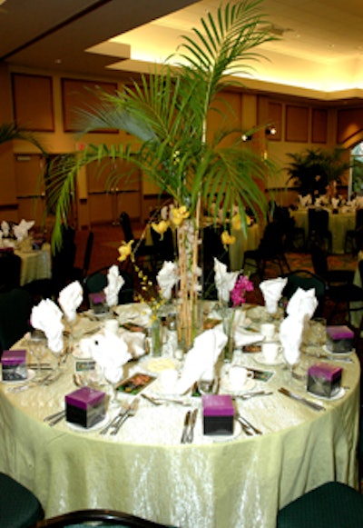 Tall cylinder centerpieces filled with orchids and topped with billowing palm fawns were set atop tables draped in cool green linens inside the ballroom.