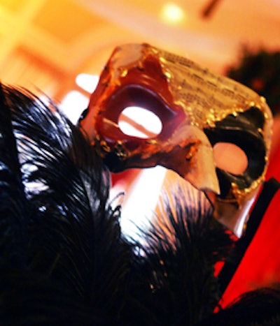 Large black ostrich feather centerpieces featuring Venetian-style masks decorated each table.