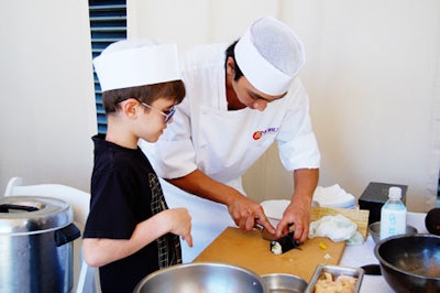 Nobu chef showing a child how to roll sushi