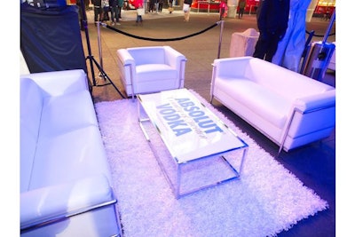 Branded lounge areas with white sofas, tables, and shag carpet filled the tent.