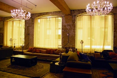 On the second floor cocktail space, windows are tinted and give the room a golden glow. Chandeliers hang from the ceiling and a bar stretches down one wall.