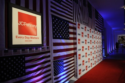 Running along the wall behind the step-and-repeat was a large collage of American flags, ranging in size from eight by five feet to six by four inches.