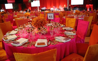 Gold-rimmed dinnerware and orchid centerpieces topped cheery tables covered in fuschia and orange.