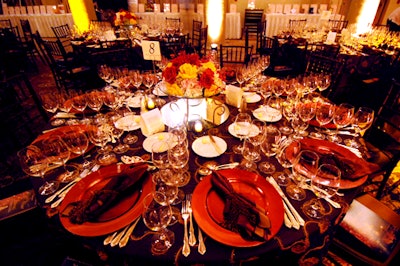 The tables were draped with dark garnet linens with gold accents and topped with compact arrangements of red and yellow roses courtesy of Deco Productions.