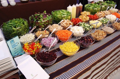 Chefs tossed various fresh items in front of guests at a salad bar.