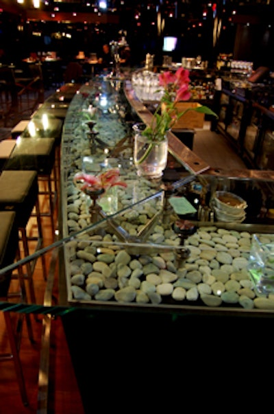 Pebbles and flowers are displayed inside the glass-topped bar.