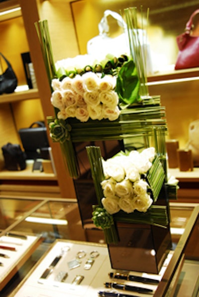 Inside the renovated boutique, ornamental displays of white roses were stacked within green reeds accented by a blossom designed at the intersecting corners.