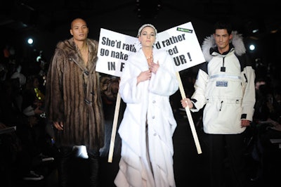 A model dressed in a white mink coat walked the runway with two male models carrying signs saying, 'She'd rather go naked in fur.'