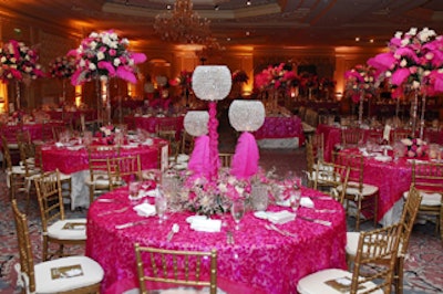 Xquisite Events use of hot pink linens, ostrich plumes, and flowers along with an abundance of crystals, amazed guests.