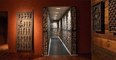 A Yorumba fetish door stands outside the stone-lined hallway. In ancient times, North African tribes used similar doors to signify rooms housing sacred objects.