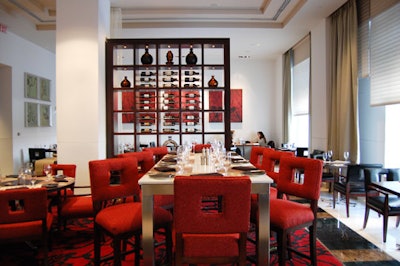 The steel-and-marble communal center table offers high dining with red upholstered chairs.