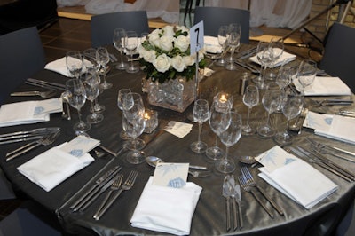 Tables topped with metallic tablecloths and crystal vases holding white rose bouquets dressed the dining area.
