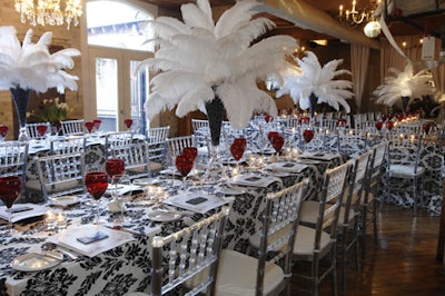 Designing Trendz topped the long dining tables with black- and-white damask print linens, red glassware, and large plumes of white feathers.