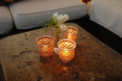 Tealights placed in orange mosaic candleholders and simple vases containing freesia topped tables on the terrace.