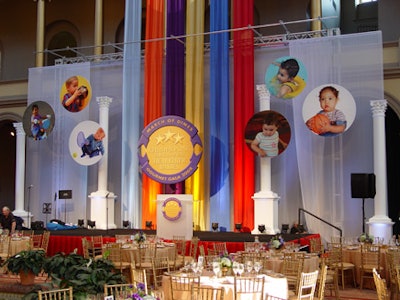 The stage featured Olympic-style decor, with floating circular pictures of babies (reminiscent of the Olympic logo) and white Greek columns.