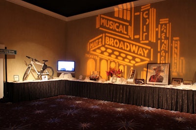 Projections of Broadway marquees decorated walls behind bars and silent auction items.