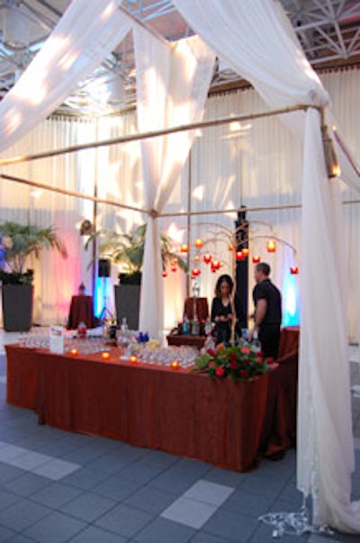 Tall golden trees adorned with hanging tealights topped two bars set beneath white draped fabric.