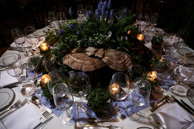 Fungi provided the base for Rock Shelter Landscape Design & Construction's woodland-inspired centerpiece. Designers nestled moss, ferns, and flowering plants between the mushrooms. Tiny pots of pansies and moss-lined votive holders surrounded the display.