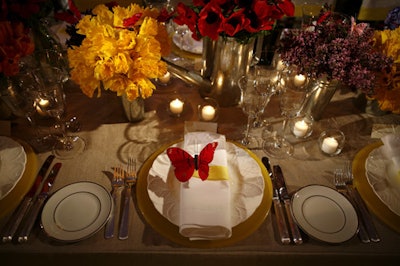 Van Vliet & Trap's colorful table included a runner of bouquets arranged monochromatically in containers like milk bottles and watering cans. Silk butterflies topped each guest's plate and dotted the floral arrangements.