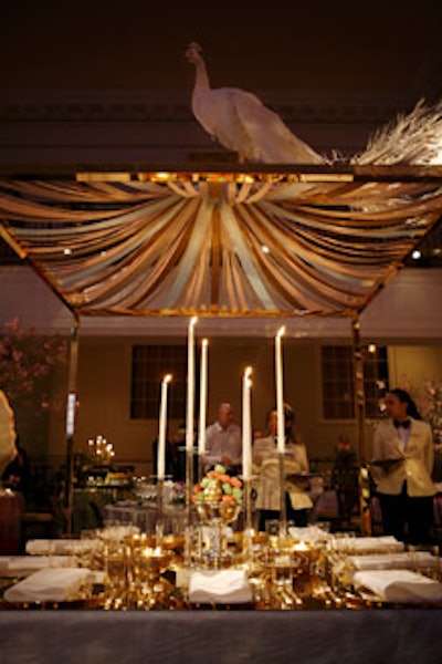 Antony Todd created an elegant golden pavilion surrounded by cube ottomans. On the table, Todd used few flowers—only some cut gardenias floating in bowls—and pushed the gilded look with a shiny golden tabletop surface, chargers, and flatware.