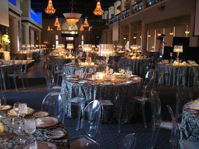 Philippe Starck Ghost chairs surrounded tables topped with silver damask linens.