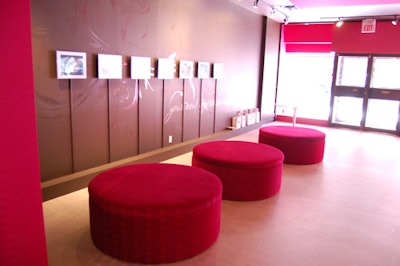 The front room of the studio has plush pink seating and TV screens showing beauty tips for hairstylists and makeup artists.