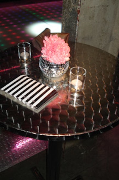 Simple pink flowers placed in mirrored glass vases topped cocktail tables throughout the space.