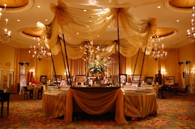 Gold fabric hung from tall metal poles covered in sheer black fabric, which created the look of bamboo rods, at the bar in the silent-auction room.