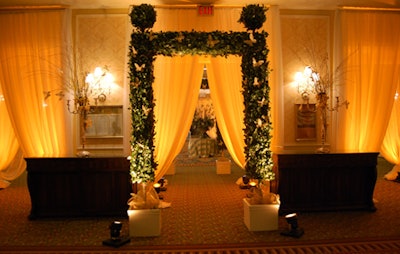 Draped fabric and archways made of greenery and decorated with sparkly gold butterflies created separate spaces in the reception area.
