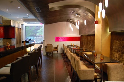 The dining space designated for dinnertime guests has velvet banquettes along one wall and an undulating brown textured ceiling.