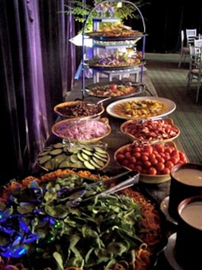 A salad bar featured a selection of vegetables to choose from, including cucumbers, onions, tomatoes, and mushrooms.