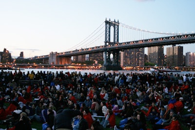 The crowd stared at the lights changing on the Brooklyn Bridge, while the Manhattan Bridge stood neglected behind them.