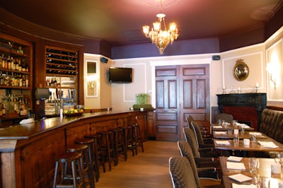 The darker end of the dining room, with tufted leather benches and upholstered armchair seating, includes a 10-seat dark wood bar.