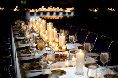 Long banquet tables covered in votive candles on mirrored pedestals lent an intimate feel to the dining room.