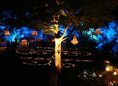 Five chandeliers (in two different formats—one globe-shaped, with strings of crystals, and the other more traditional, with electric candles) hung from a back tree, with red and white rope lights arranged on the lawn.