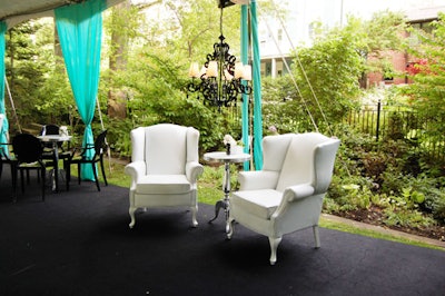Black chandeliers hung above pairs of white wing chairs inside the tent.