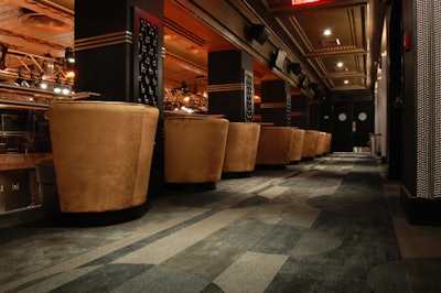 The upstairs balcony, featuring plush seating and illuminated glass tiles, overlooks the main ballroom.