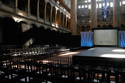 Rows of glossy black bamboo chairs surrounded the elevated runway on three sides.