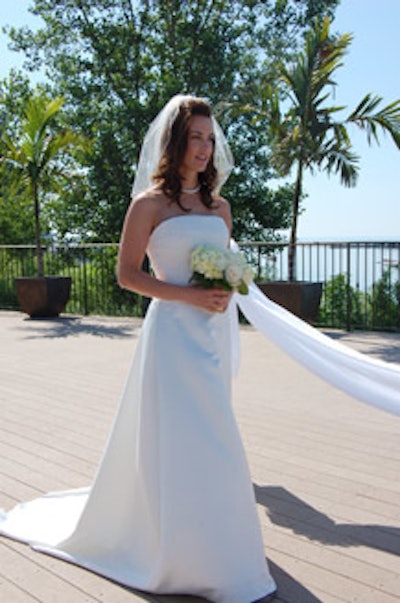 The bride, dressed in a traditional white wedding gown, walked down the aisle to 'Here Comes the Bride.'