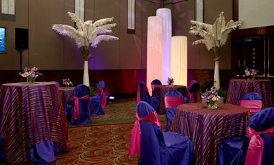 Linens in the updated tropical lounge vignette featured a purple satin underlay, cranberry sheer stripe overlay, and purple satin chair covers with raspberry-colored chair ties.