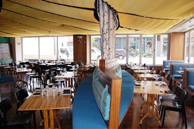 In the main dining room, a wooden banquette wraps around a line of white birch trees, whose tops are obscured in the fabric-draped ceiling.