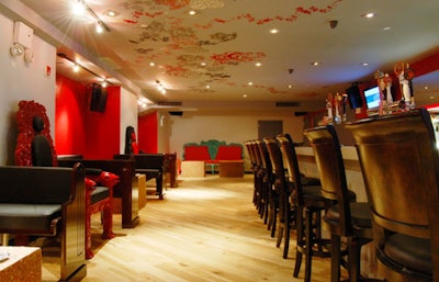 Adjacent to the main performance area is a public bar, accented with red walls, custom furniture, and hardwood flooring.