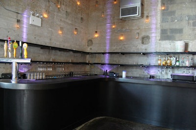 The L-shaped bar sits on the main floor and, unlike the rest of the space, is lit with blue lighting and candle light.