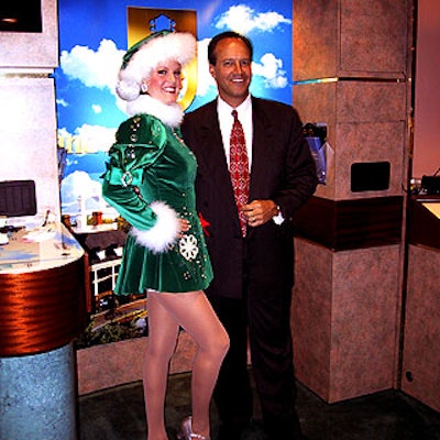 Radio City Rockette Cheryl Hebert posed with David DuBois, president and CEO of Professional Convention Management Association, in front of the Opryland Hotel Group display at Meeting World 2001 at the New York Hilton.