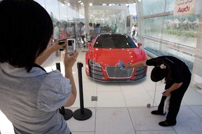 Guests at the Volkswagen pavilion look at cars from the other side of glass displays.