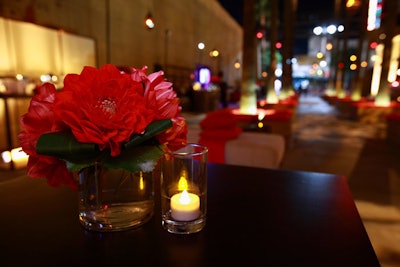 Red floral centerpieces and candles sat on black lounge tables.