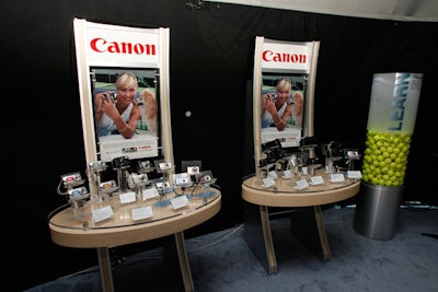 A table displayed several Canon PowerShot cameras along with their specs, in front of a blown-up ad featuring Sharapova.