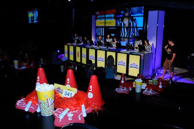 Containers filled with popcorn topped guest tables decorated with cheerleading pom poms, branded foam hands, and plastic megaphones.
