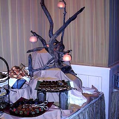 Large pieces of driftwood decorated with candles in mini hanging holders sat on Abigail Kirsch Culinary Productions' food tables.